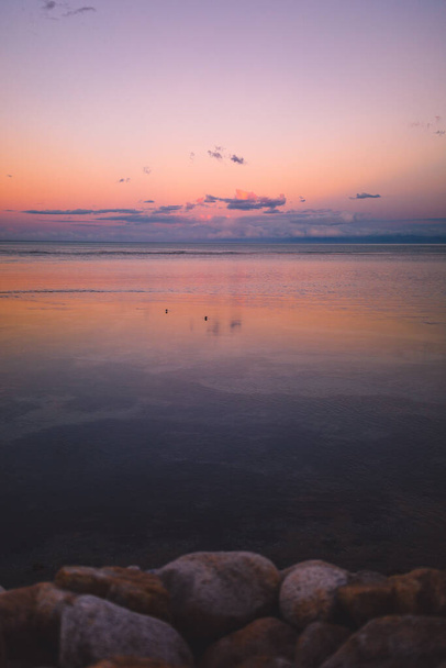 A vertical shot of stones on the beach and the beautiful sunset in Marahau, New Zealand - Photo, image