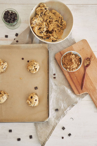 A vertical top view of chocolate chips dough balls on an oven tray - 写真・画像