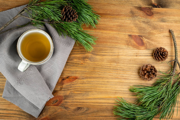 Βελόνες πεύκου τσάι σε λευκό κύπελλο top view με χώρο αντίγραφο. Υγιεινό ποτό το χειμώνα στο κάμπινγκ, πεύκο δέντρο βελόνες τσάι σε κούπα. Scurvy ιατρική, πηγή βιταμίνης C και καροτένιο - Φωτογραφία, εικόνα