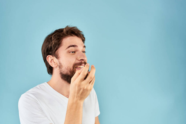Эмоциональный мужчина с бородой в белой футболке синего фона весёлый образ жизни - Фото, изображение