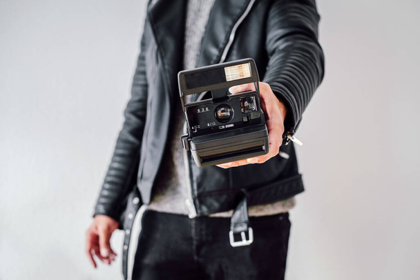 A person with a leather jacket holding a camera against a white wall - Photo, image