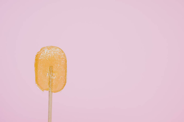 A closeup shot of orange-flavored lollipop isolated on pink background - Fotoğraf, Görsel