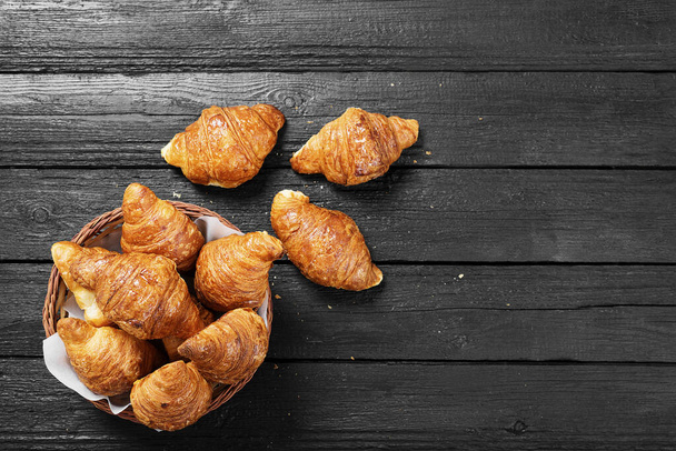 Freshly baked croissants on black wooden table, top view. - Photo, Image