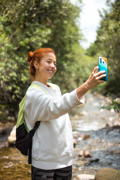 A vertical shallow focus shot of a female with ginger har taking a selfie in nature - Фото, зображення