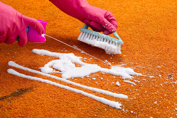 Nainen käsi puhdistus tahra matolla kovalla harjalla. lähikuva Oranssi matto märkäpuhdistus. maton siivouspalvelu käsite - Valokuva, kuva