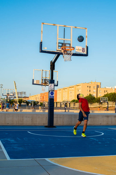 A vertical shot of a boy playing basketball wearing a sanitary mask-concept of the new normal - Photo, Image