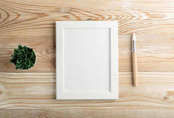 Ahşap masa üzerinde fırçaları ve manzarası olan asgari sanatçı modeli. Beyaz kağıt arkaplan oluşturur, kopyalama alanı ile resim çerçevesi - Fotoğraf, Görsel