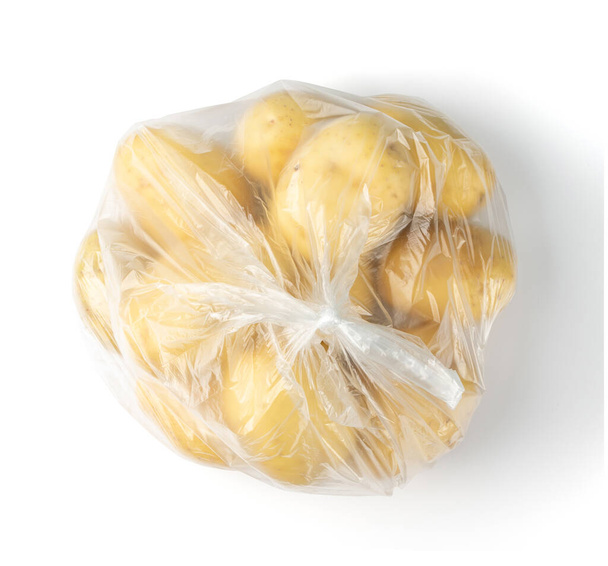 Surowe całe ziemniaki w plastikowej torbie izolowane na białym tle widok z góry. Żółte umyte bio ziemniaki - Zdjęcie, obraz