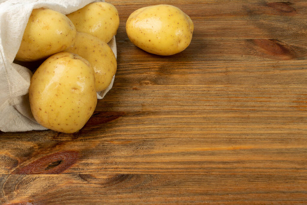 Pieu de pommes de terre entières crues sur fond bois vue de dessus. Modèle de pommes de terre lavées jaunes sur motif de texture de planche vintage avec espace de copie - Photo, image