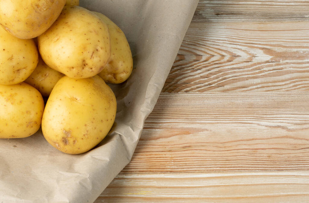 Raw whole potato pile on wooden background top view. Yellow washed potatoes mockup on vintage board texture pattern with copy space - Photo, Image