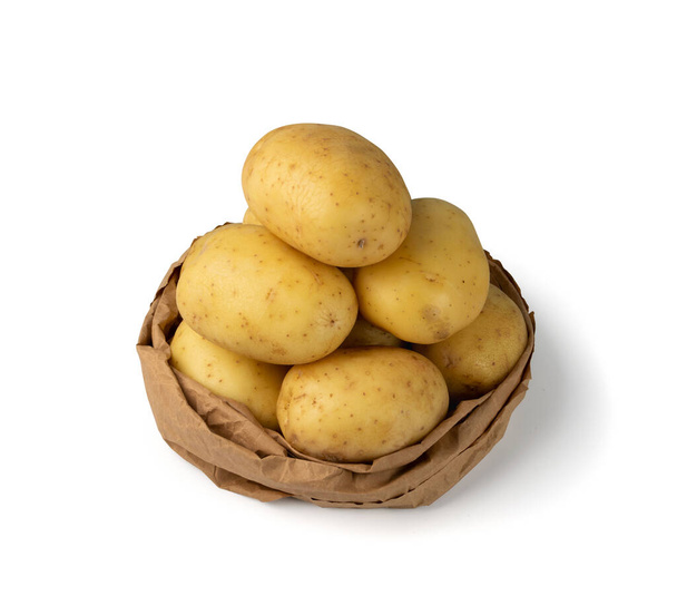 Rohe ganze Kartoffelstapel isoliert auf weißem Hintergrund mit Schnittpfad. Gelbe gewaschene Bio-Kartoffeln in Papiertüten-Attrappe - Foto, Bild