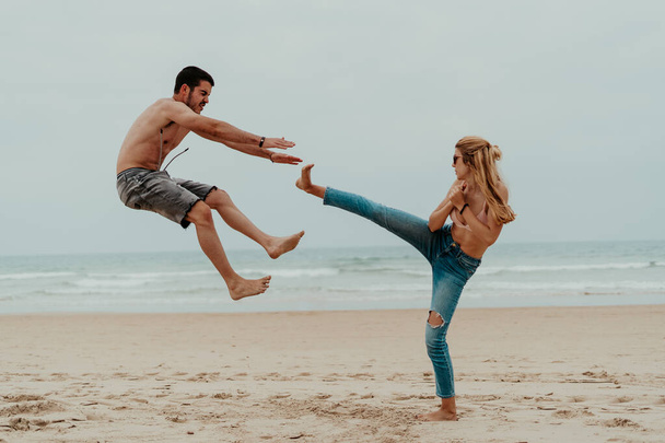 Una competencia masculina VS femenina - una hembra haciendo un movimiento de karate y golpeando al macho haciendo que caiga - Foto, Imagen