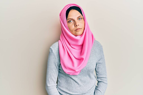 Mujer caucásica joven que usa bufanda islámica tradicional de hiyab relajada con expresión seria en la cara. simple y natural mirando a la cámara.  - Foto, Imagen