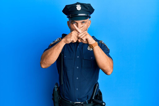Hombre guapo de mediana edad con expresión de rechazo uniforme de la policía cruzando dedos haciendo signo negativo  - Foto, Imagen