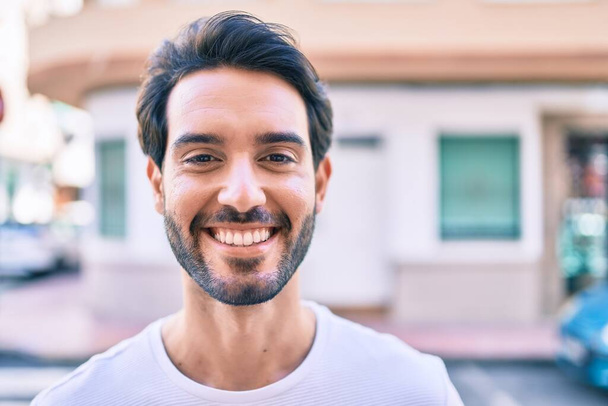 Jonge Spaanse man glimlachend blij lopend naar de stad. - Foto, afbeelding