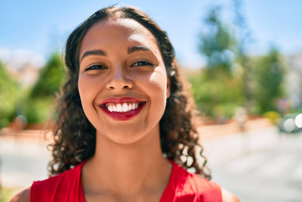 Genç Afrikalı Amerikalı kız gülümseyerek şehirde mutlu bir şekilde yürüyor.. - Fotoğraf, Görsel