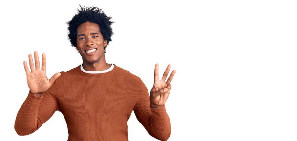 Jóképű afro-amerikai férfi afro hajjal, alkalmi ruhában, a nyolcadik ujjal mutogatva, miközben magabiztosan és boldogan mosolyog..  - Fotó, kép