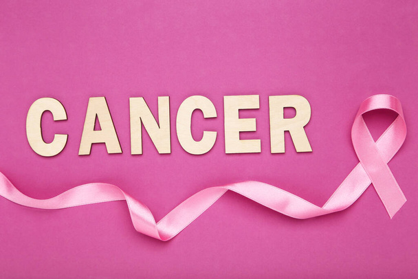 Ribbon and inscription Cancer on pink background - Foto, imagen