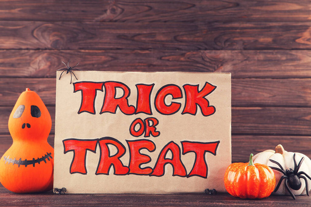 Text Trick or Treat with pumpkins and spiders on wooden background - Foto, afbeelding