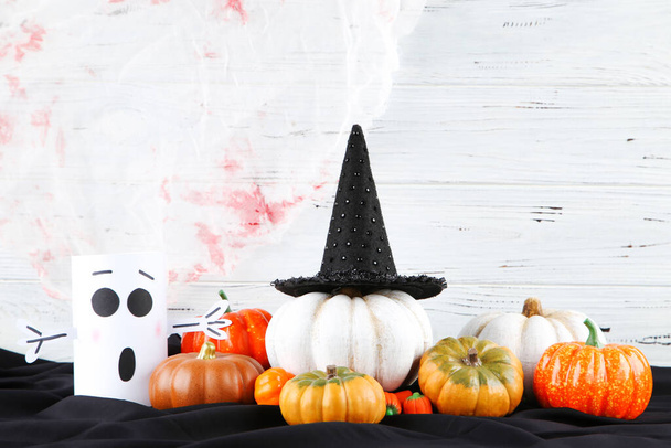 Halloween pumpkins with paper ghost and candies on wooden background - Fotó, kép