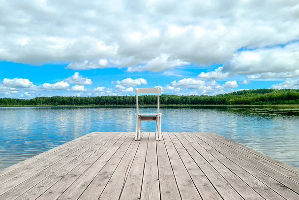 Blanco silla cubierta vacía en el muelle del lago. - Foto, imagen