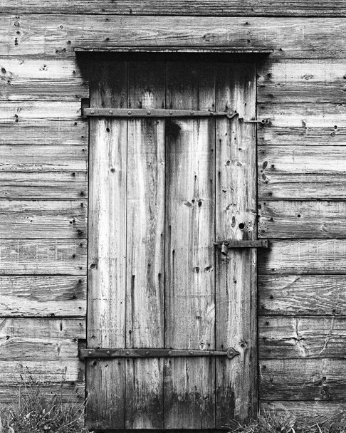 Vintagepuu ovi rauta saranat riippulukossa suljettu hylätyssä rakennuksessa. Kuva kuvattiin analogisella filmillä. - Valokuva, kuva