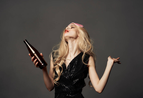 Belle blonde avec une bouteille de bière à la main et un masque rose sur la tête - Photo, image