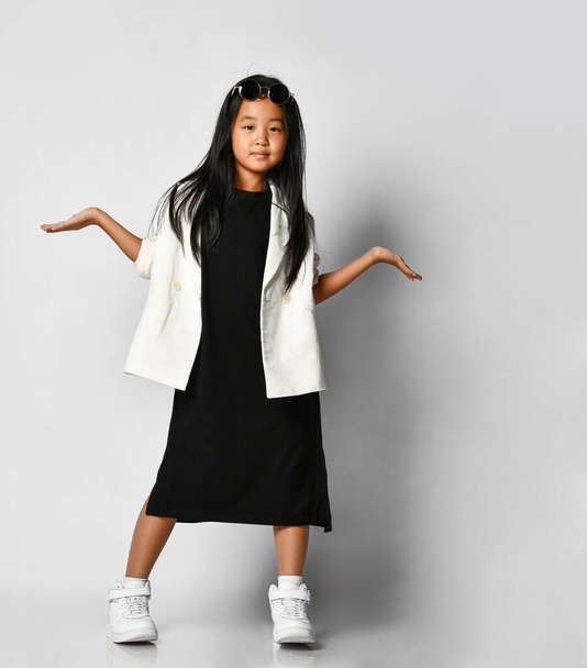 Little asian girl model posing in studio on a white background with outstretched hands. - Foto, Imagem