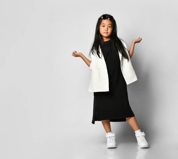 Little asian girl model posing in studio on a white background with outstretched hands. - 写真・画像