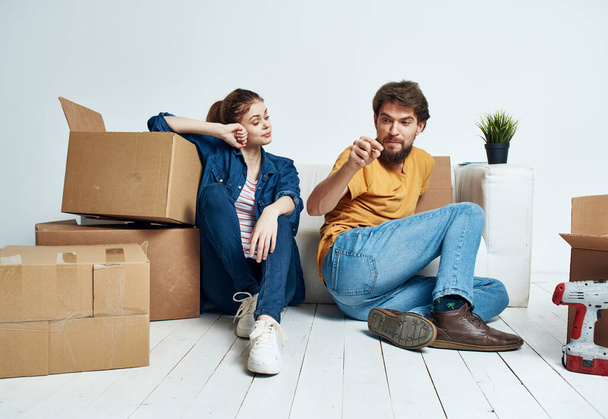 Married couple man and woman on wooden floor with boxes moving flower in a pot repair work - Foto, Imagem