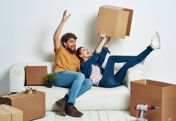 familia joven pareja en el sofá divertido mover cajas con cosas - Foto, imagen