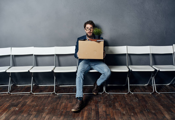 Man sitting on white chair waiting for lighting box job search depression - Valokuva, kuva