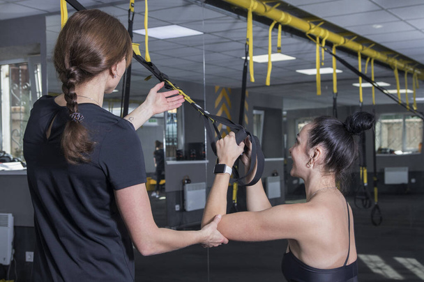 Las mujeres hacen ejercicio en el gimnasio con correas de bucle de equipo - Foto, imagen