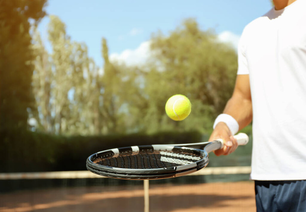 Sportsman playing tennis at court on sunny day, closeup - Φωτογραφία, εικόνα