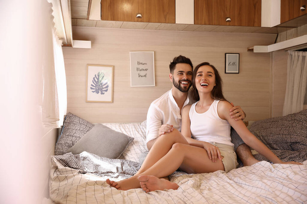 Happy young couple on bed in trailer. Camping vacation - Foto, immagini