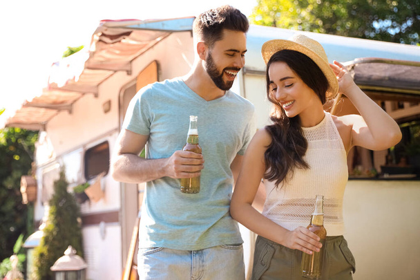 Happy couple with bottles of beer near motorhome. Camping season - Foto, Imagem