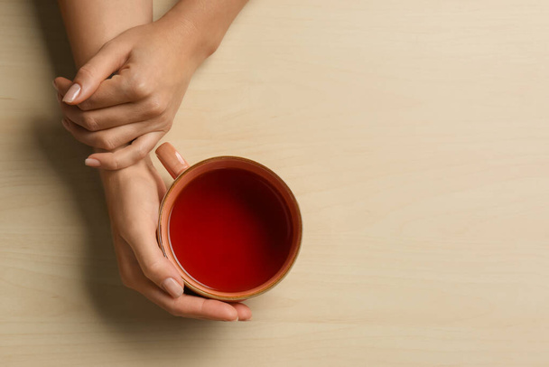 Woman holding cup of tea at wooden table, top view. Space for text - 写真・画像