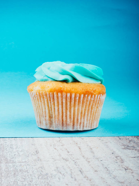 gustoso Cupcake o muffin con glassa crema di formaggio blu su tavolo di legno e sfondo blu con spazio per il testo - Foto, immagini