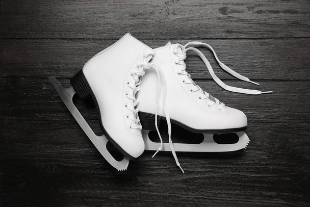 Pair of skates on black wooden background, flat lay - Foto, afbeelding