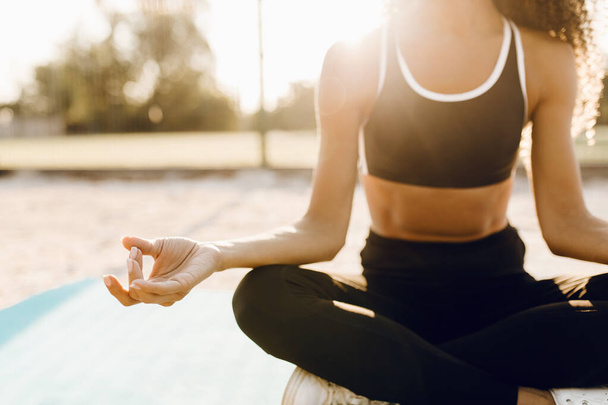 Giovane donna sportiva che fa yoga in posizione di loto su un tappeto fitness all'aperto nel parco - Foto, immagini