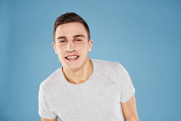 Hombre emocional en camiseta blanca vista recortada sobre fondo azul estilo de vida - Foto, Imagen