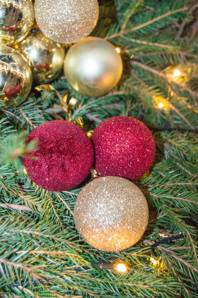 自然のモミの枝の背景にかわいいクリスマス輝く赤と金のガラスボール、モミの枝や装飾、垂直フレームと本格的なクリスマスの背景. - 写真・画像