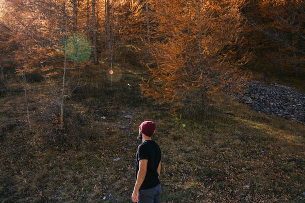 Молодой парень в хорошей физической форме и в хипстерском стиле стоит лицом к лесу - Фото, изображение