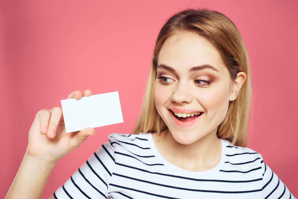 Woman with a business card in her hands a striped T-shirt pink background Copy Space advertising - Photo, Image