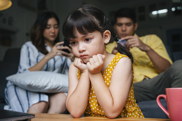 Asiática niña siendo ignorado por sus padres en casa. Problema de adictos sociales. - Foto, Imagen
