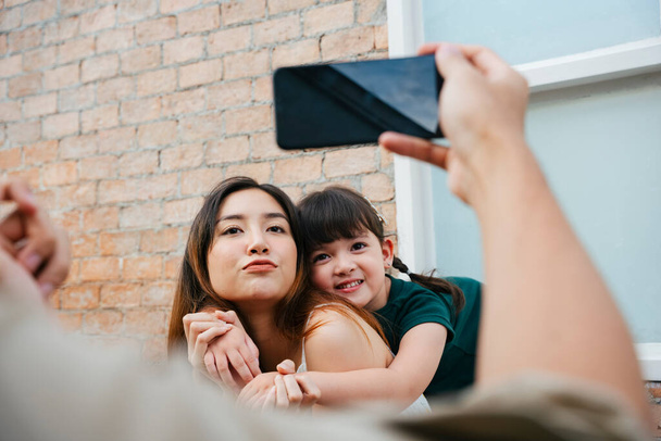 aziatische moeder en dochter nemen foto met smartphone samen thuis. - Foto, afbeelding