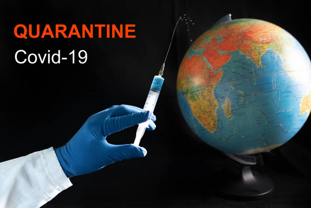 Hand with a medical syringe on the background of the globe of the planet. The concept of a coronavirus. - Fotó, kép