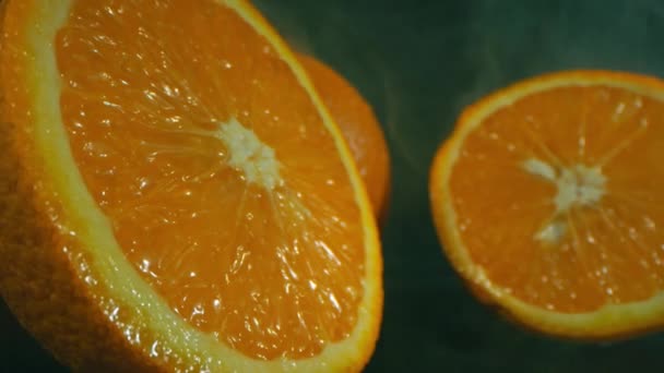 Inzoomen macro stilleven beelden van gesneden oranje fruit in zwarte achtergrond met licht rook effect - Video