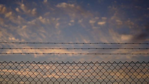valla de alambre de púas contra la puesta del sol - Foto, Imagen