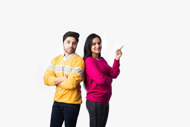 Asian Indian couple wears colourful warm sweater or woolen winter cloths, standing isolated against white background - Photo, Image